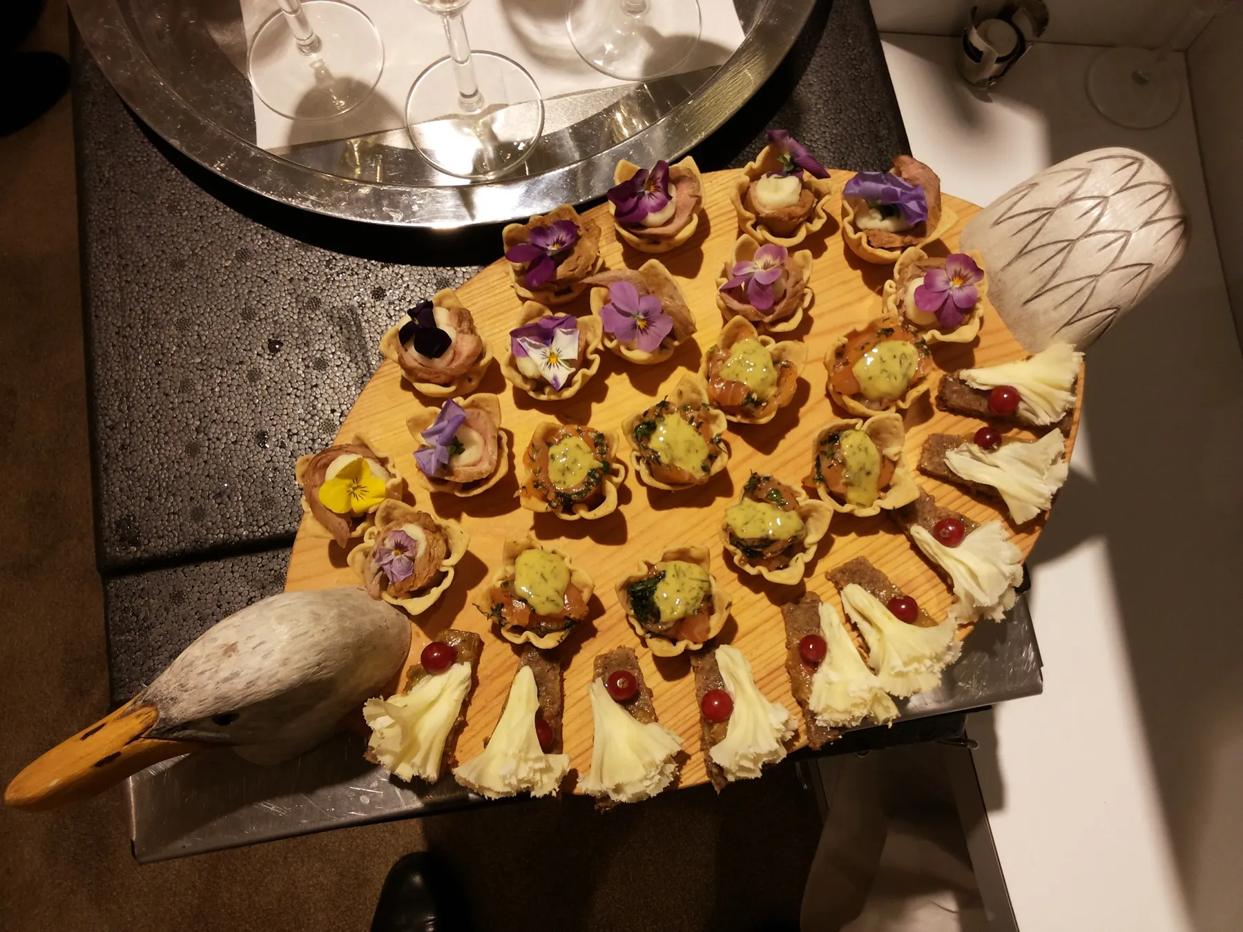 Houten serveerplank met canapés en eetbare bloemen