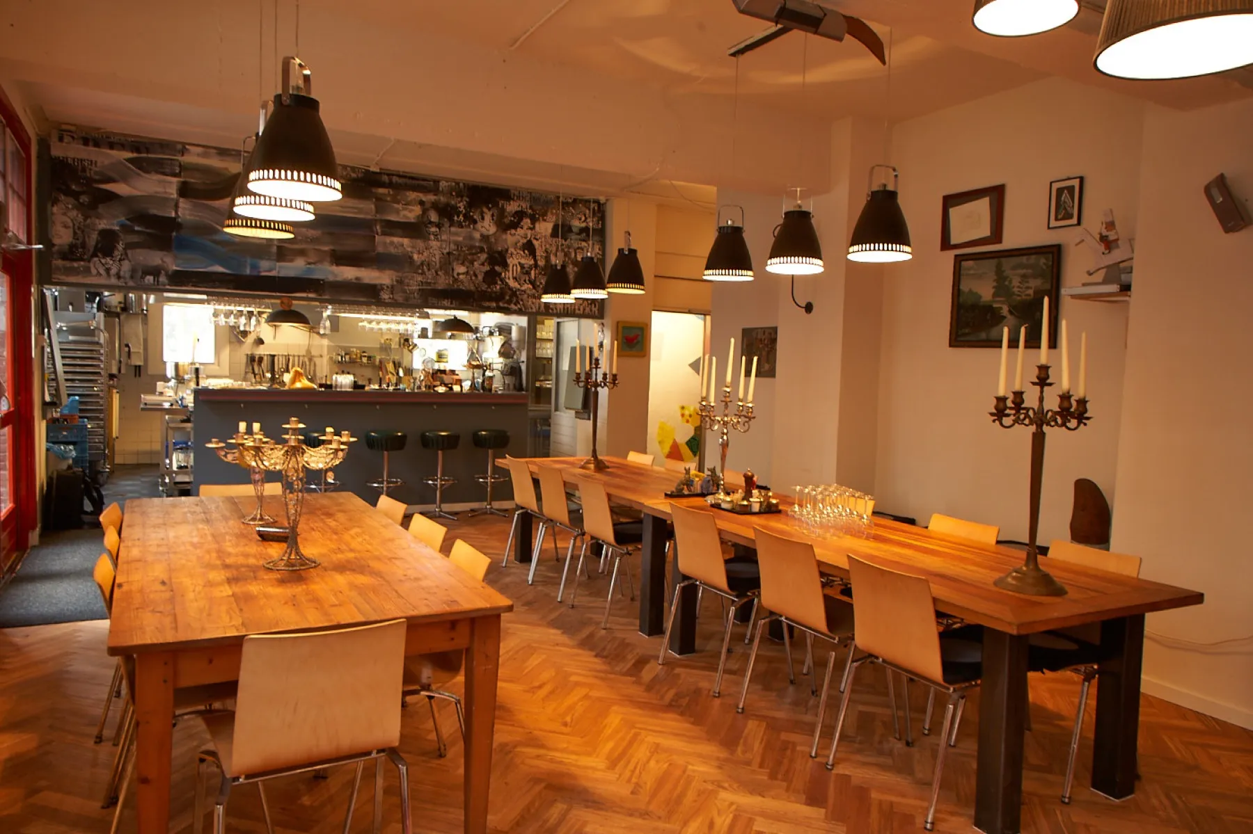 Het kookatelier: twee lange houten tafels, kandelaars en open keuken